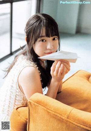 A woman sitting on a bed surrounded by white balloons.