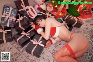 A woman in a bunny costume sitting on a bed next to a Christmas tree.