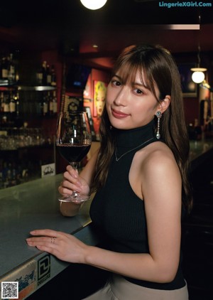 A woman sitting on a couch holding a glass of wine.