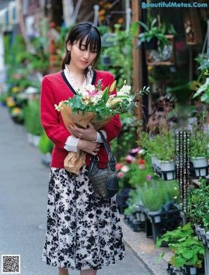 A woman in a black bra and glasses holding a flower.