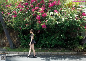 A woman in a black bathing suit standing in front of a window.